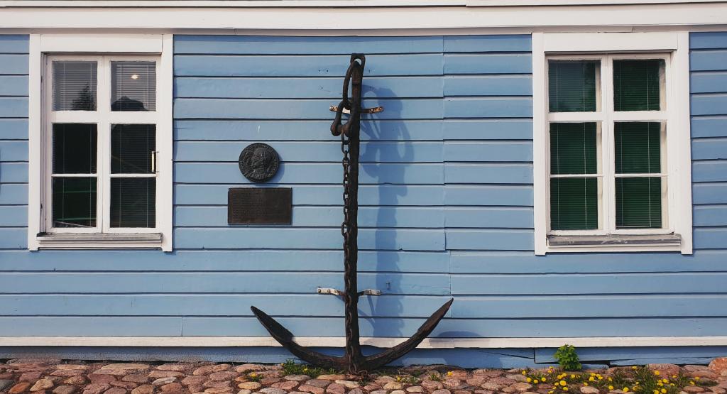 Pakkahuoneen museon seinää koristavat muun muassa ankkuri ja Myhrbergin muistolaatta. Kuva: Raahen museo. Ankkuri Pakkahuoneen museon seinustalla. Kuva: Raahen museo.